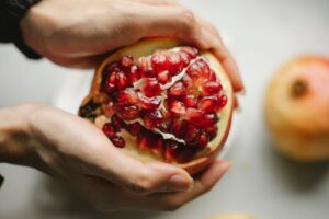 Close-up of hands holding fresh pomegranate displaying vibrant seeds, perfect for healthy eating concepts.