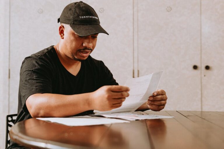 Adult man sitting at home table, focused on reviewing important documents.