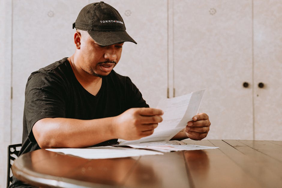 Adult man sitting at home table, focused on reviewing important documents.