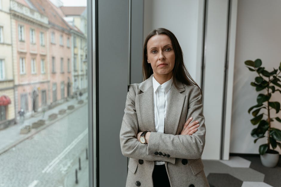 Businesswoman in formal attire by a window, showcasing confidence and professionalism.