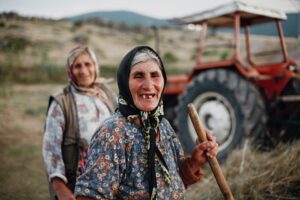 Two elder women farmers with a tractor in a rural field.