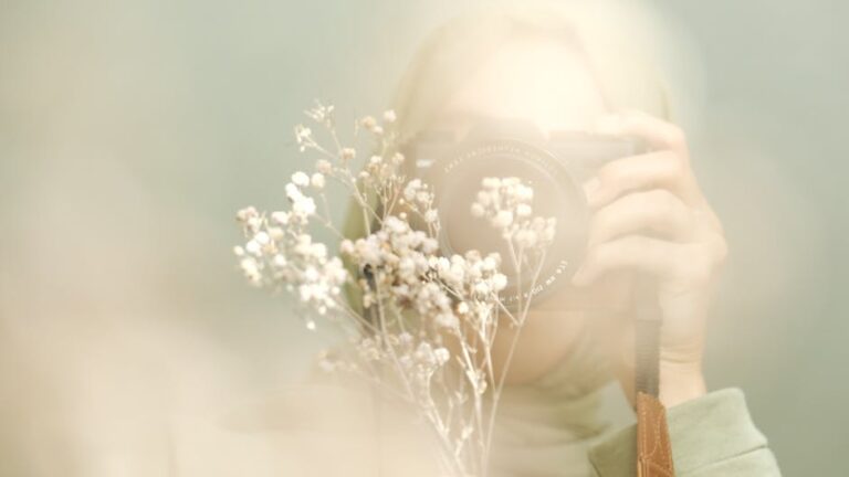 Blurry artistic portrait showing a person with a camera and delicate flowers.