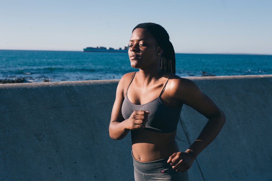 A young woman in activewear jogging along the ocean, embracing a healthy lifestyle.