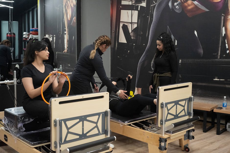 Three women engaging in Pilates exercise with equipment inside a gym studio.