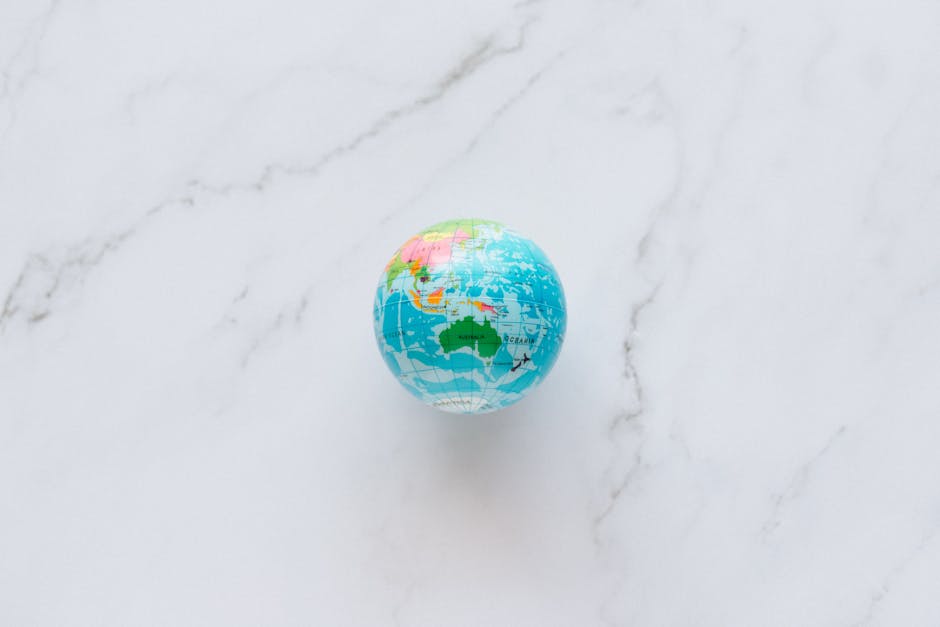 A small, colorful globe rests on a marble surface, symbolizing global exploration and travel planning.