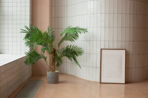 A minimalist interior design featuring a potted palm plant and a blank frame against tiled walls.