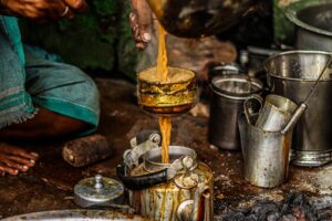 Close-up of a traditional tea brewing process with rustic utensils and steaming tea.