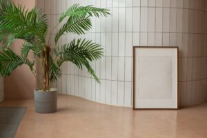 Minimalist interior featuring a potted palm and blank framed art against a tile wall.