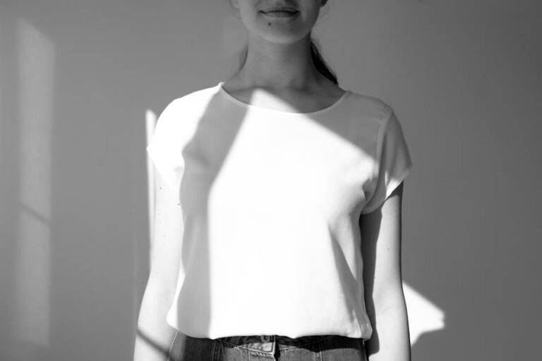 Black and white photo of a woman in a white t-shirt, with sunlight casting shadows.