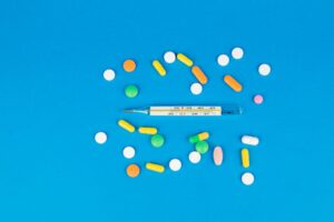 Vibrant pills and a thermometer arranged on a blue backdrop. Perfect for health and medicine themes.