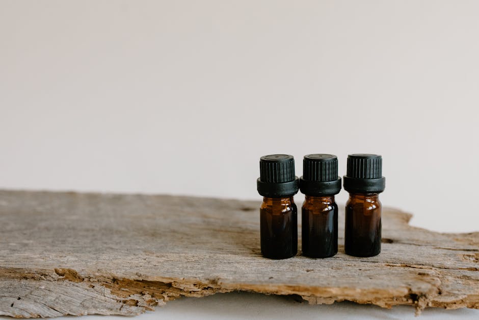 Three essential oil bottles on rustic wood surface, perfect for aromatherapy and natural healing themes.