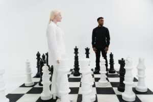 Two individuals strategize on a life-size chessboard, immersed in a game of intellect.
