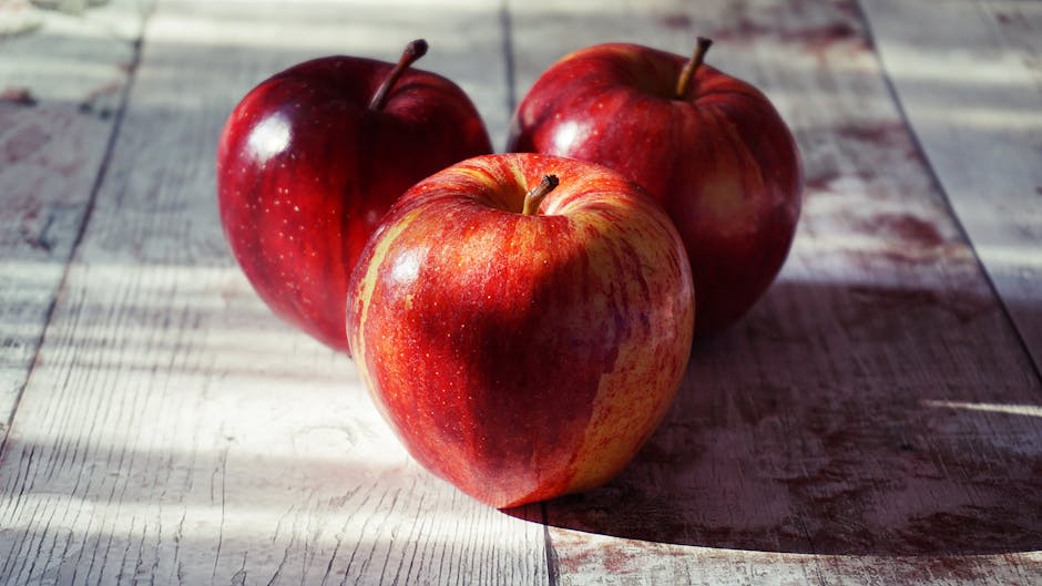 Close-up of fresh red apples on a rustic wooden table captured in natural light.